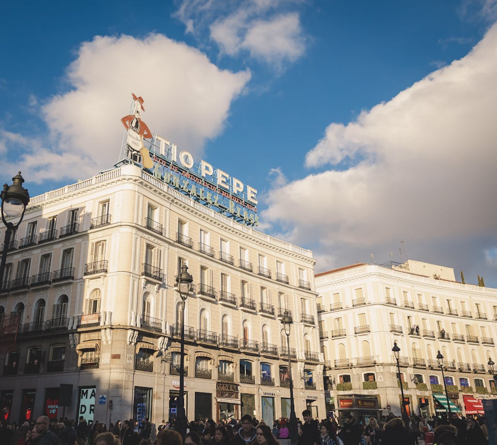 Crowded Puerta del Sol in Madrid with iconic Tio Pepe sign under a bright sky. Madrid Itinerary