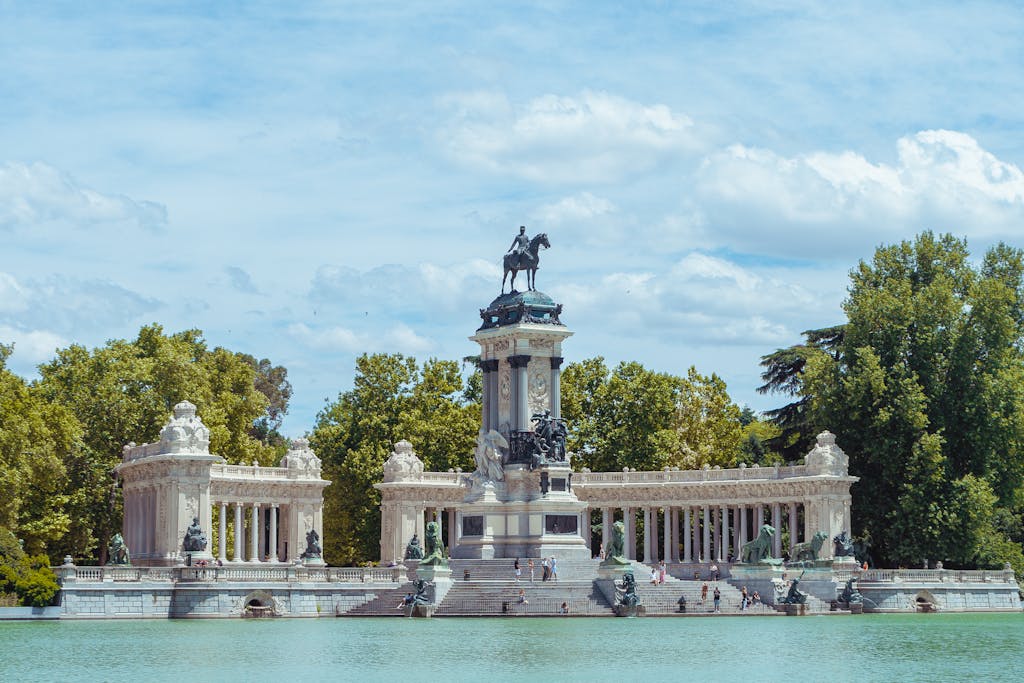 Scenic view of the Monument to Alfonso XII in Retiro Park, Madrid with a cloudy sky backdrop.