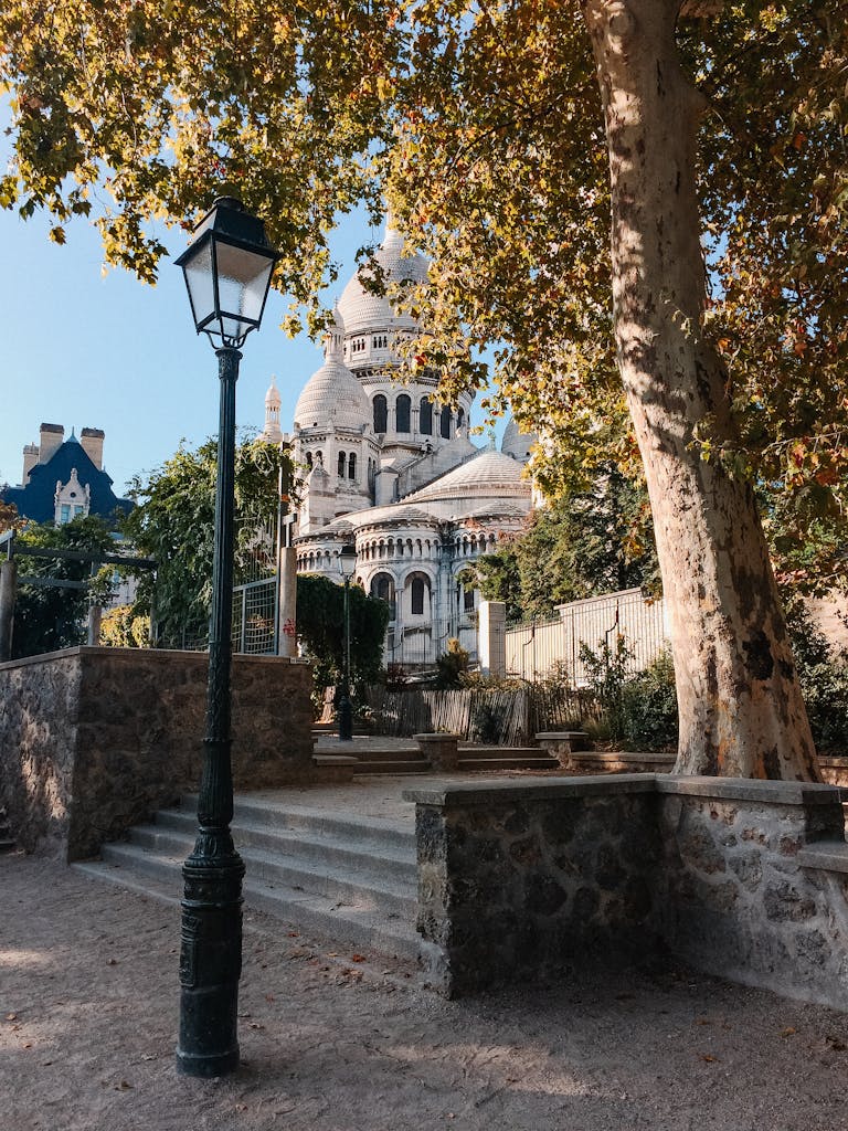 A picturesque view of Sacré-Cœur Basilica framed by trees and a classic lamp post.
