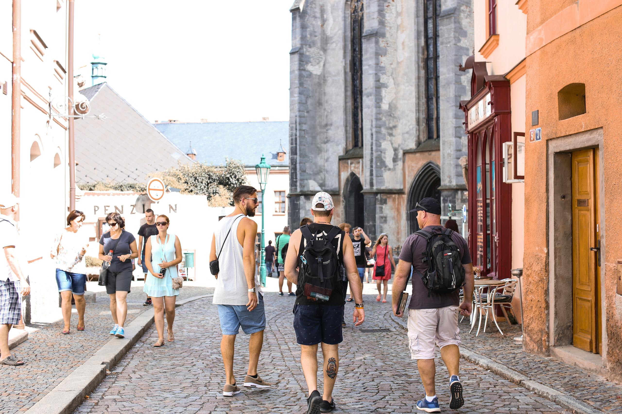 A bustling stone road in a historic European city filled with tourists enjoying a summer day.