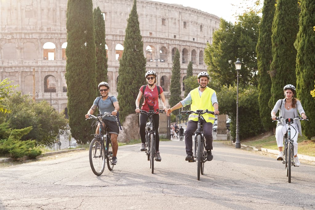 Group of cyclists enjoying a summer bike tour near the iconic Colosseum in Rome.